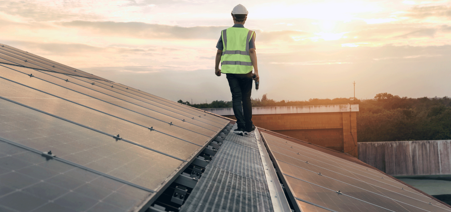 back view of a workman standing on a flat roof with no fall protection.